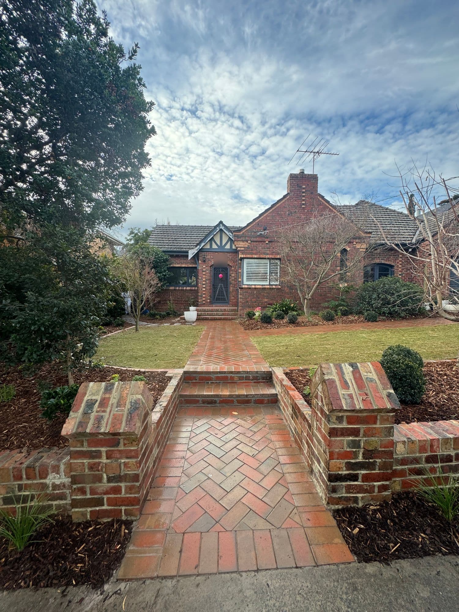 After: a herringbone brick entry between capped brick piers, with new lawns either side